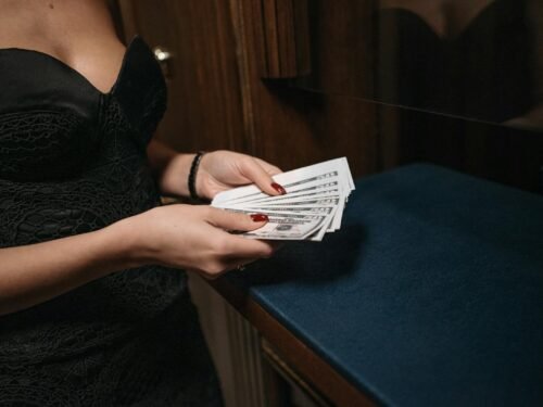 Woman in elegant dress holding money, showcasing wealth and luxury in an indoor setting.