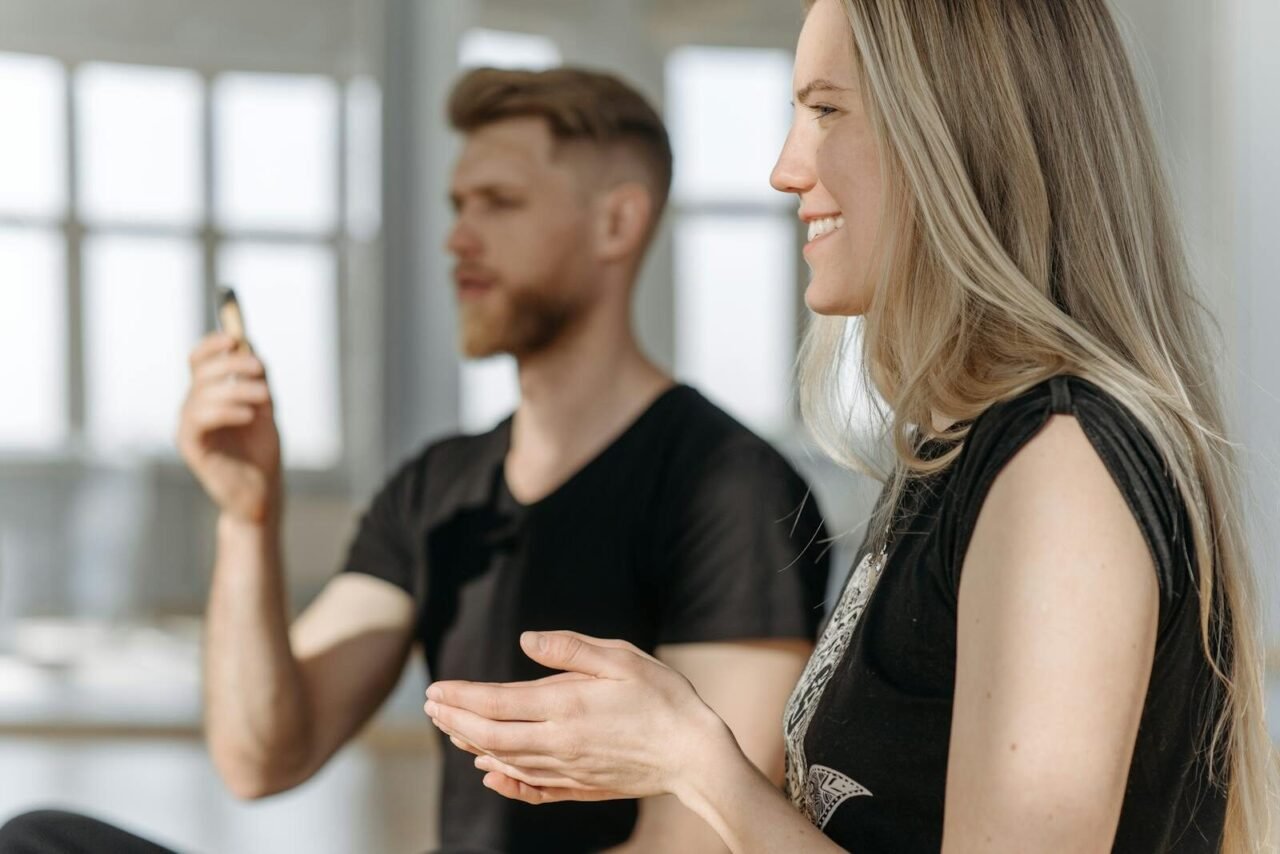 Two adults practicing meditation indoors with natural light and focus on mindfulness.