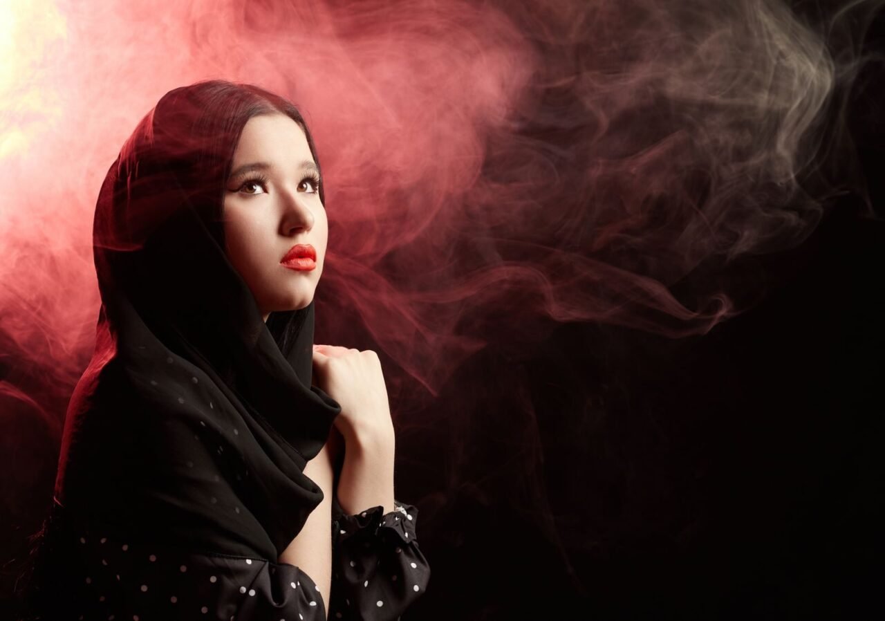 Artistic portrait of a woman in a headscarf enveloped by dramatic smoke.