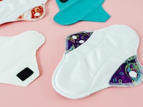 Close-up of colorful reusable menstrual pads on a pink surface, promoting eco-friendly menstruation solutions.