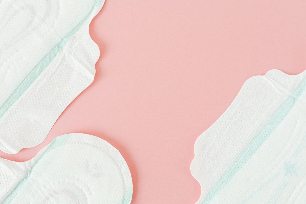 Close-up of white sanitary pads on a soft pastel pink surface, ideal for feminine hygiene themes.