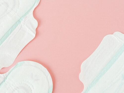 Close-up of white sanitary pads on a soft pastel pink surface, ideal for feminine hygiene themes.