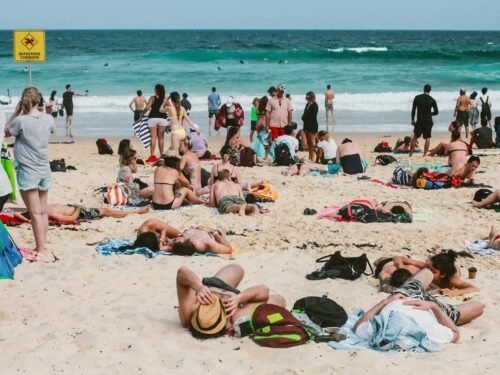 People enjoying a sunny day at Bondi Beach, Australia, with vibrant ocean waves and lively atmosphere.