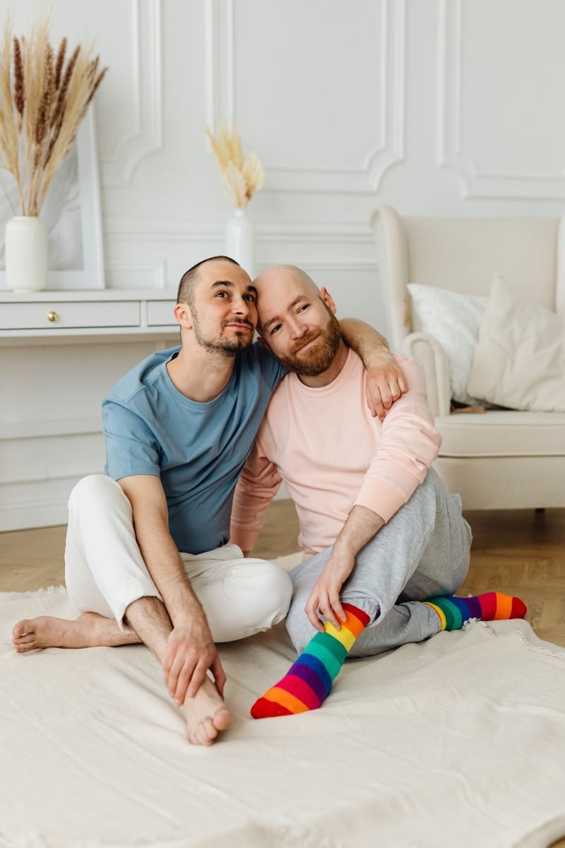 A loving couple sitting on a rug in a cozy home interior, smiling and embracing.