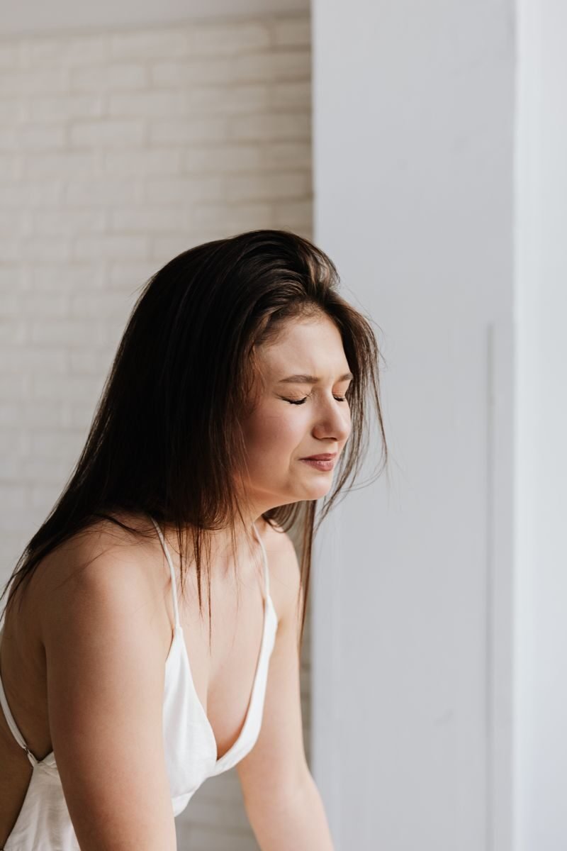 A woman expressing emotion in a bright indoor environment, shot from the side.