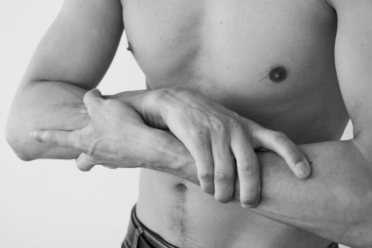 Close-up black and white photo of a shirtless man highlighting fitness and strength.