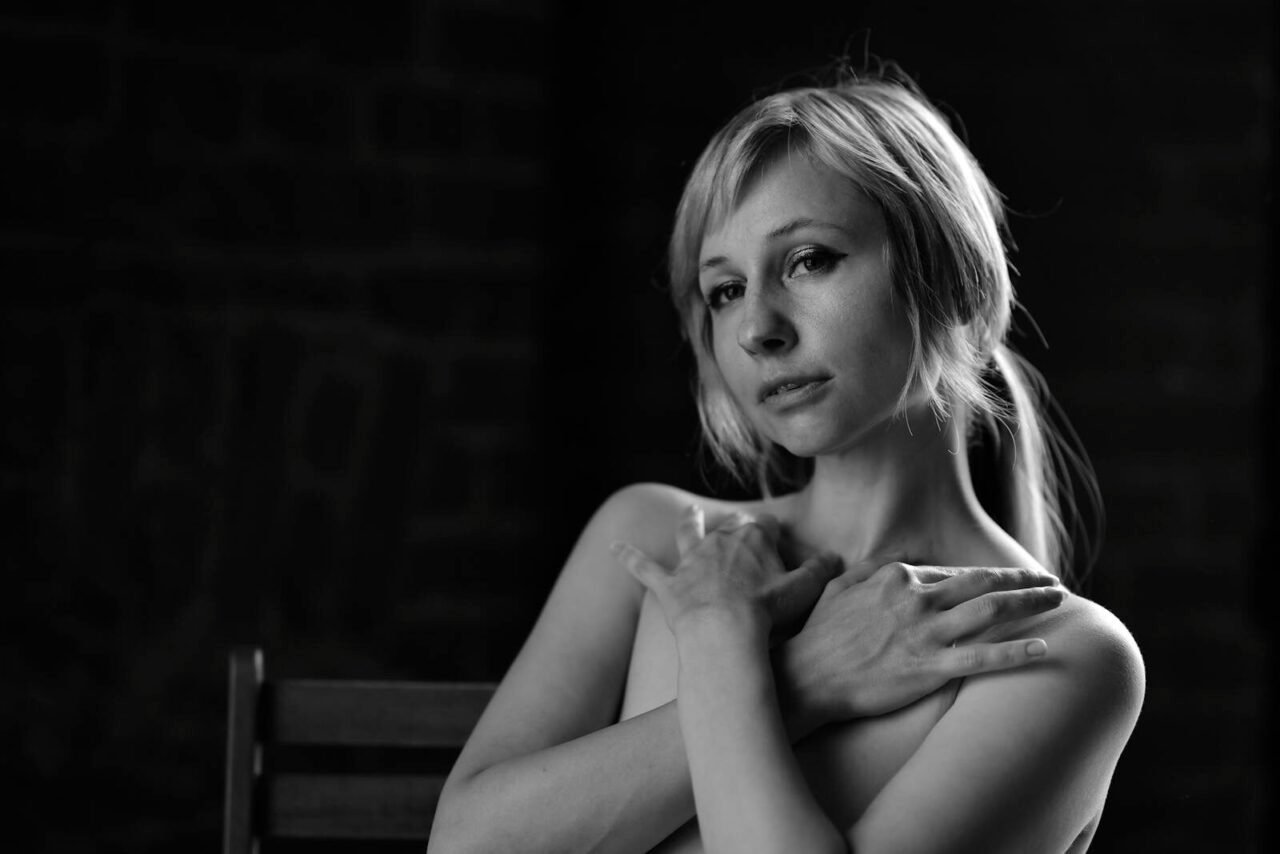 Stunning monochrome portrait of a woman embracing herself, exuding elegance and beauty.