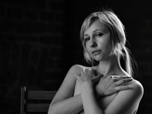 Stunning monochrome portrait of a woman embracing herself, exuding elegance and beauty.