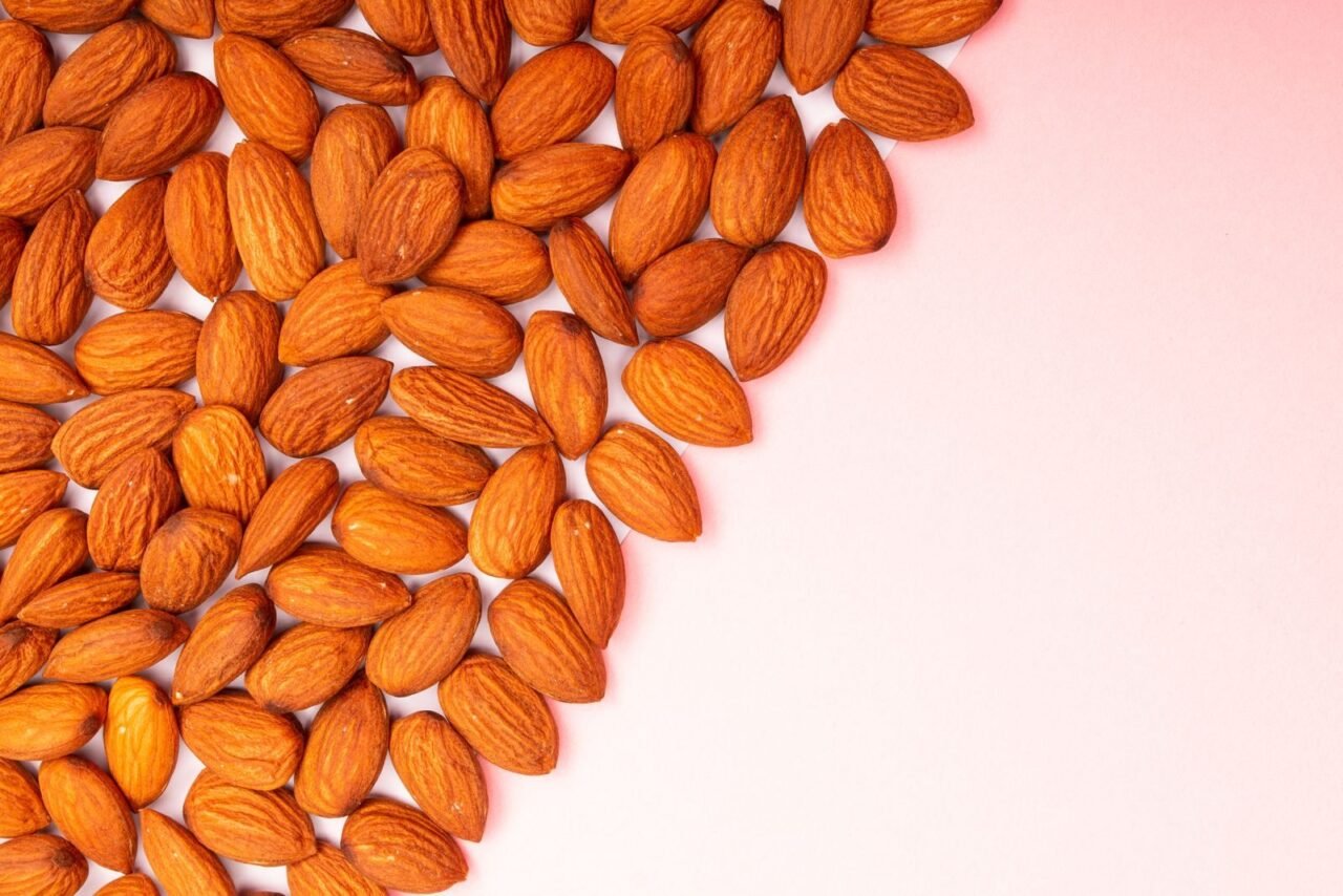 Organic almonds arranged on a pastel pink surface, perfect for health and nutrition themes.