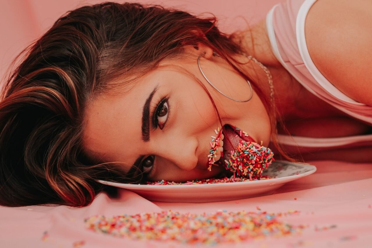 A playful portrait of a woman with sprinkles on a plate, showcasing a fun and vibrant mood.