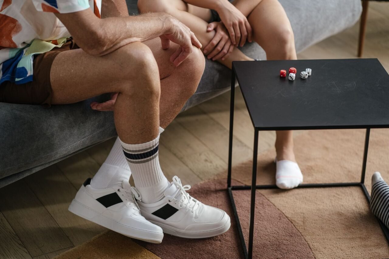 A couple sitting together playing a dice game on a black table indoors, casual atmosphere.