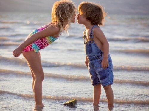 girl and boy kissing on beach during daytime
