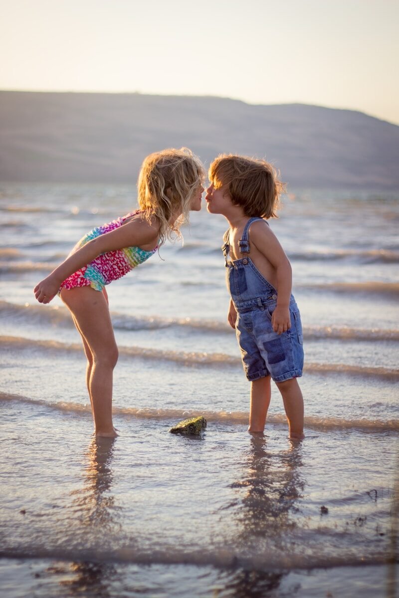 girl and boy kissing on beach during daytime