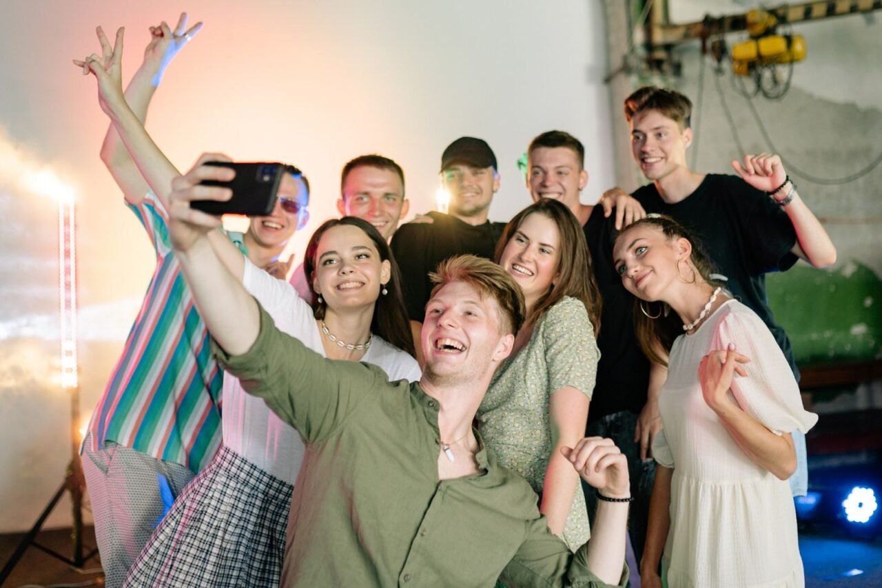 A joyful group of friends captures a selfie indoors, radiating happiness and energy.