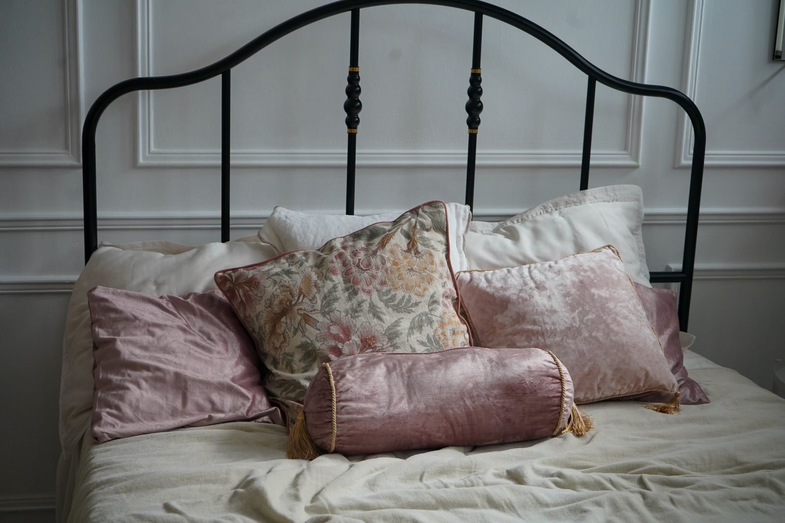 A cozy and elegant bedroom setup featuring decorative cushions and a classic bed.