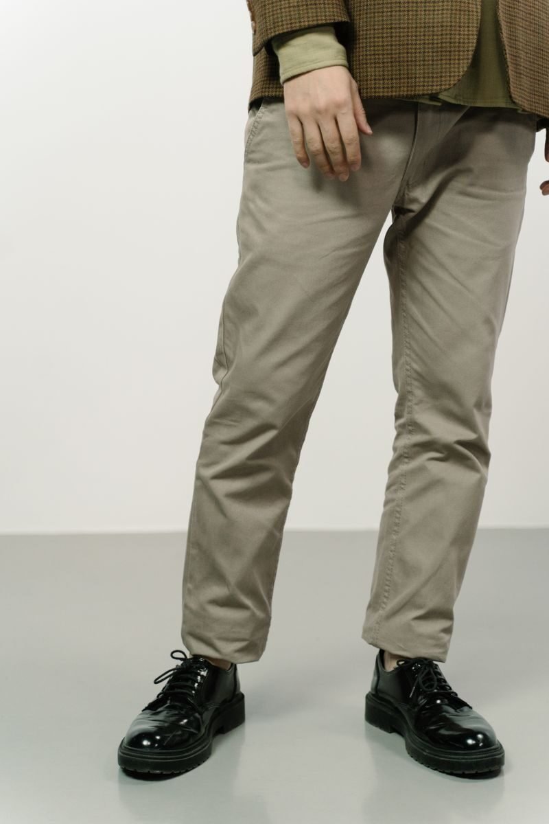 Elegant men's fashion showcasing shiny shoes and tailored trousers in a minimal setting.