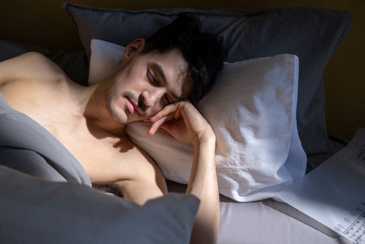 A man peacefully sleeping in a sunlit bedroom with natural light streaming in.