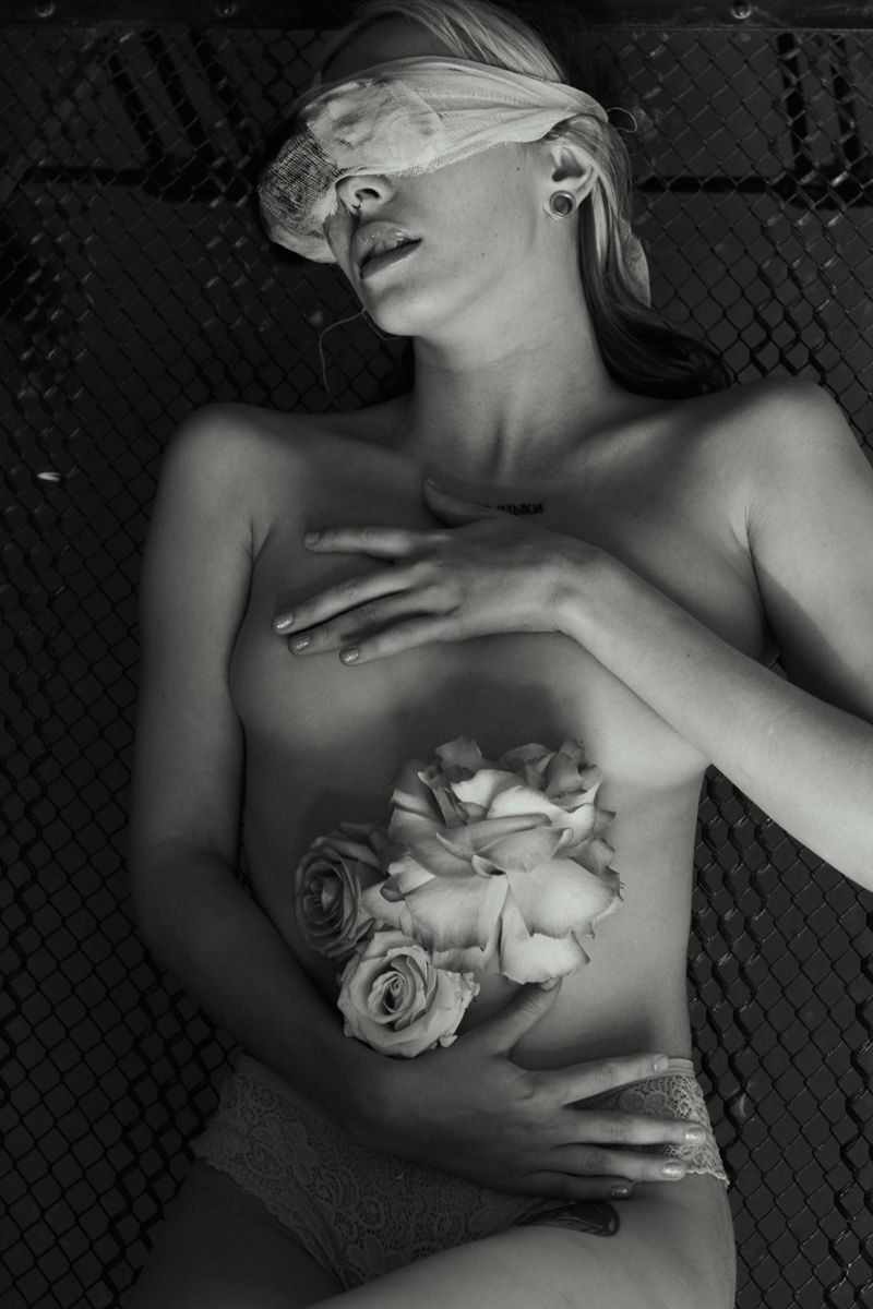 Artistic black-and-white photo of a blindfolded woman holding roses.