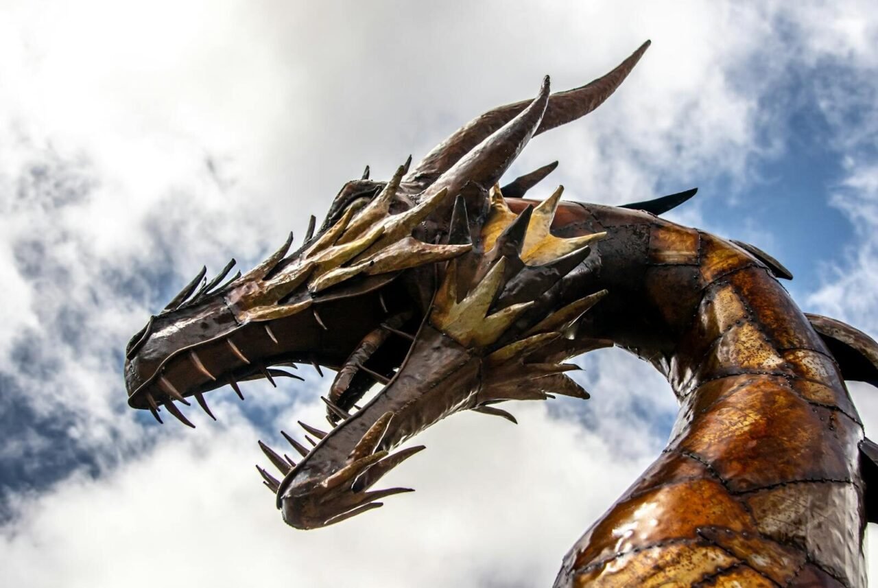 A striking low-angle view of a dragon statue set against a cloudy sky.