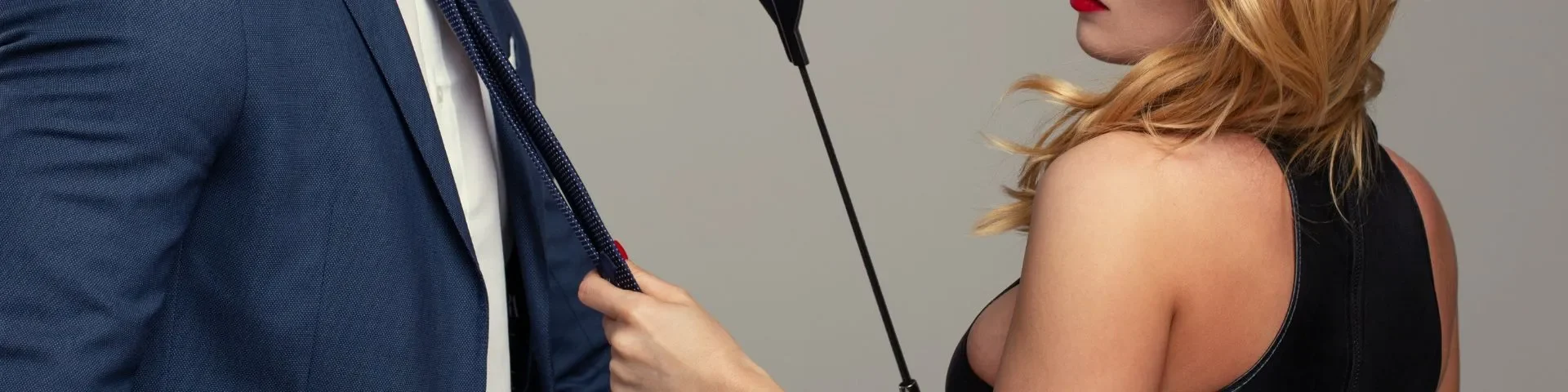 Domme holds sub by his tie