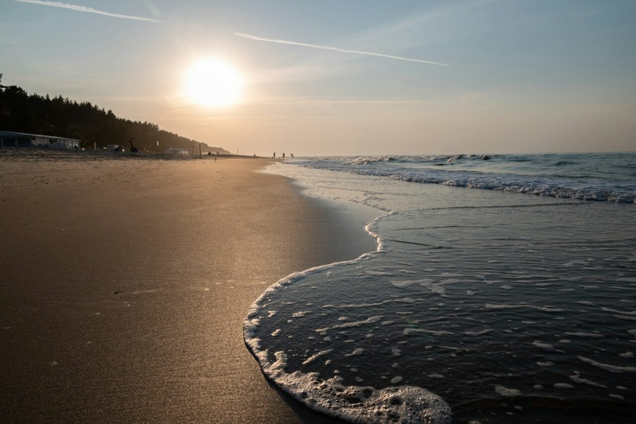 The sun is setting over the ocean on the beach