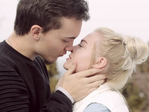 man wearing black top about to kiss woman