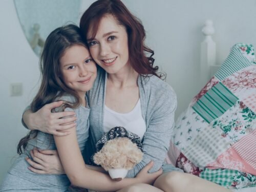 Mother and daughter embrace lovingly, smiling at the camera.