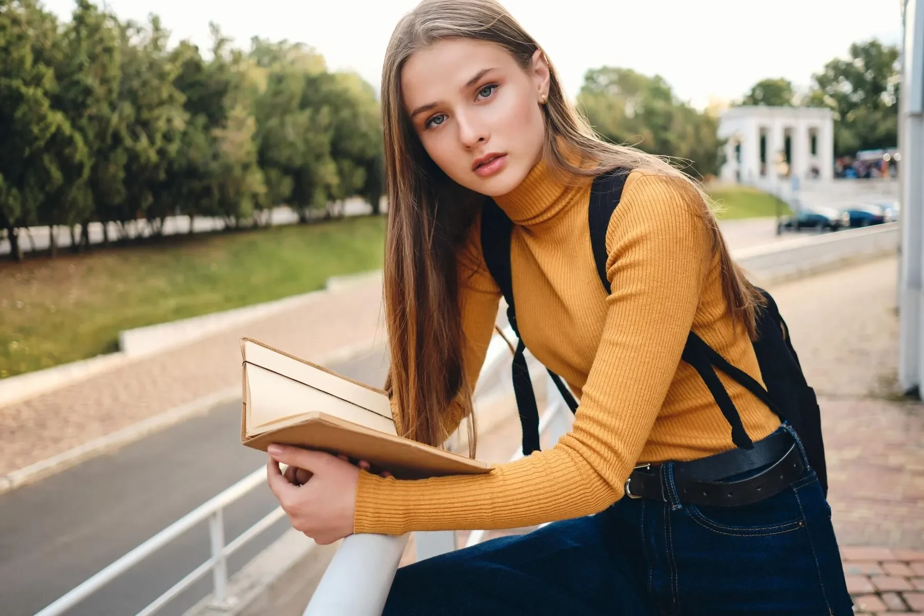 Attractive student girl with text book thoughtfully looking camera studying