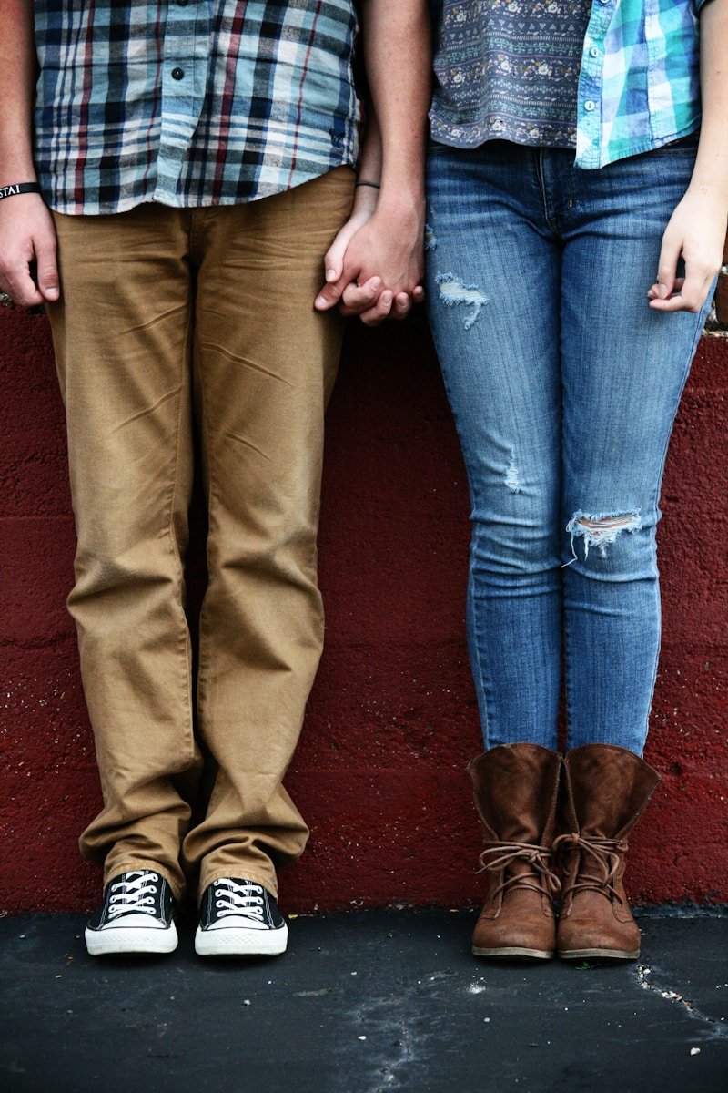 Couple holding hands, standing in front of a wall.