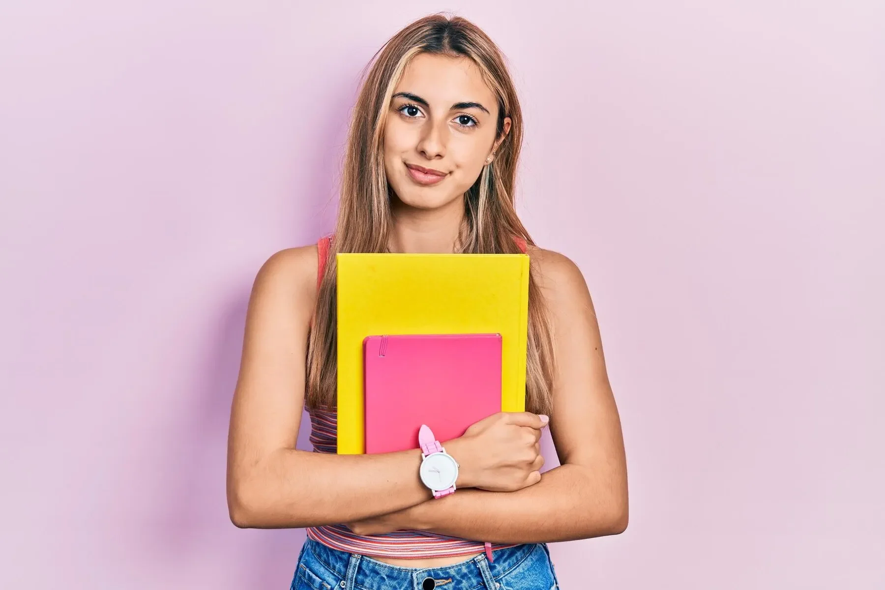 Beautiful hispanic woman holding books thinking