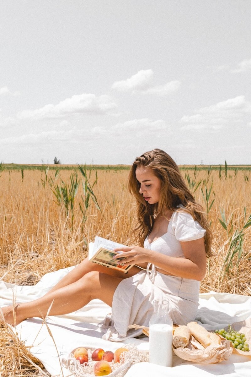 a woman sitting in a field reading a book