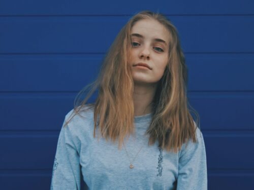 a woman with long hair standing in front of a blue wall