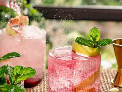 a pink drink with a mint garnish on the rim