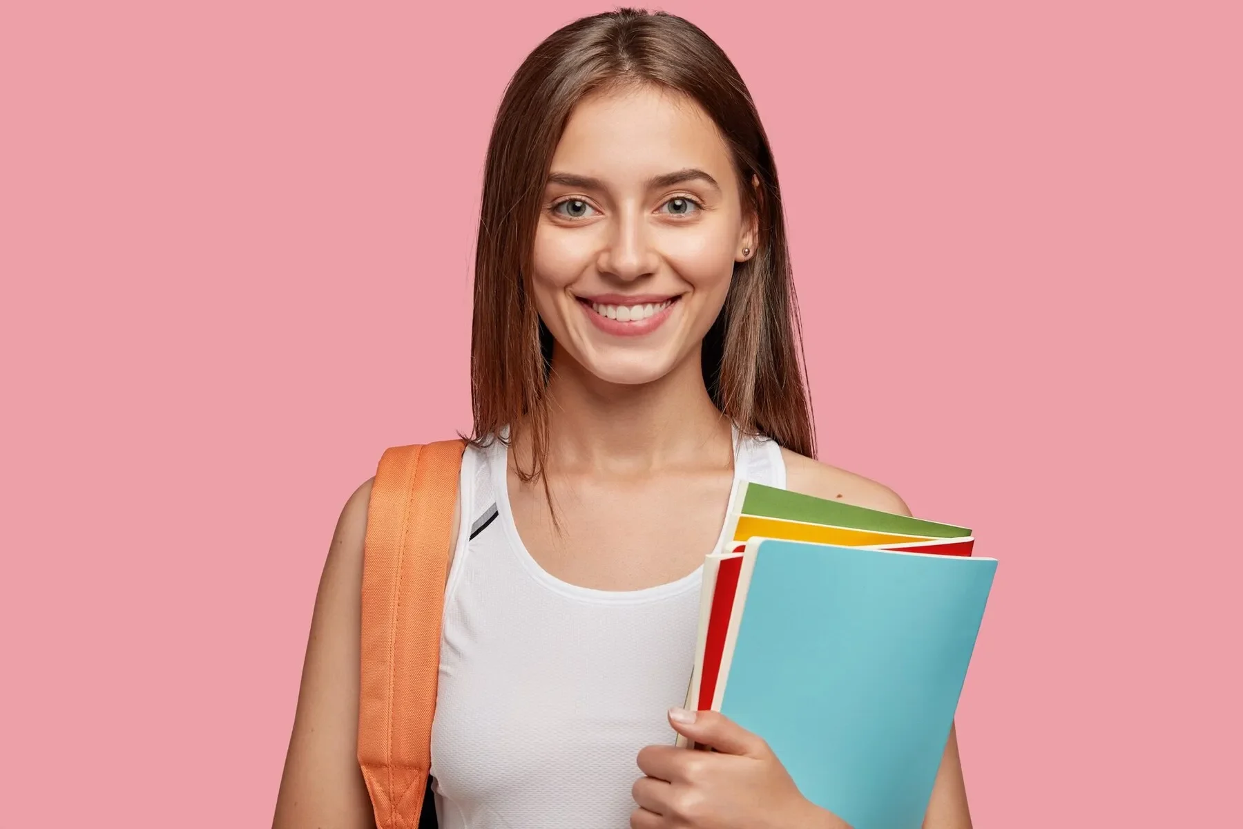 Cheerful student posing against pink wall