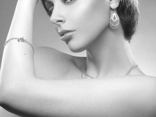 grayscale photography of topless woman covering breast and one hand on hair