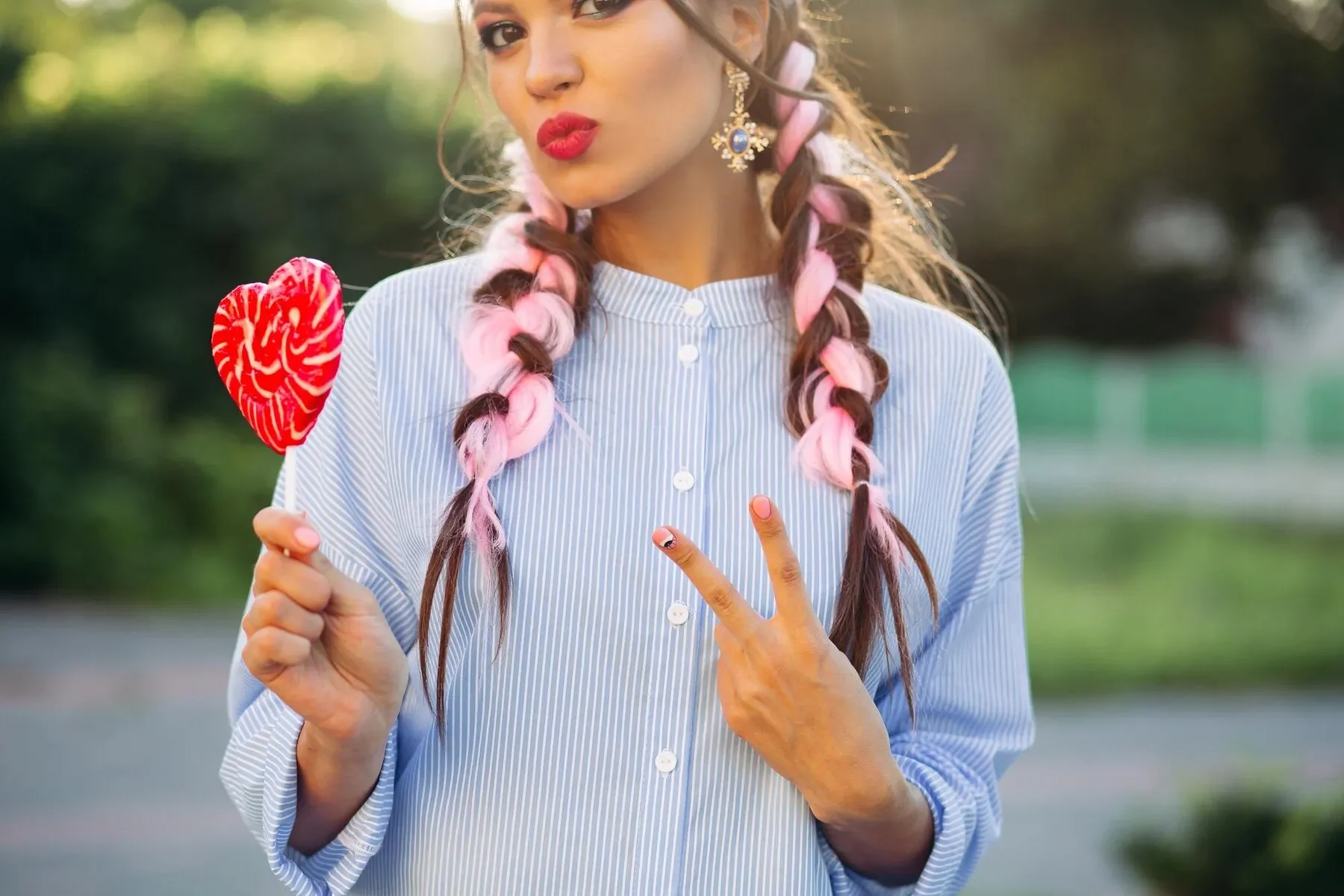 Close up girl with colorful braids holding candy