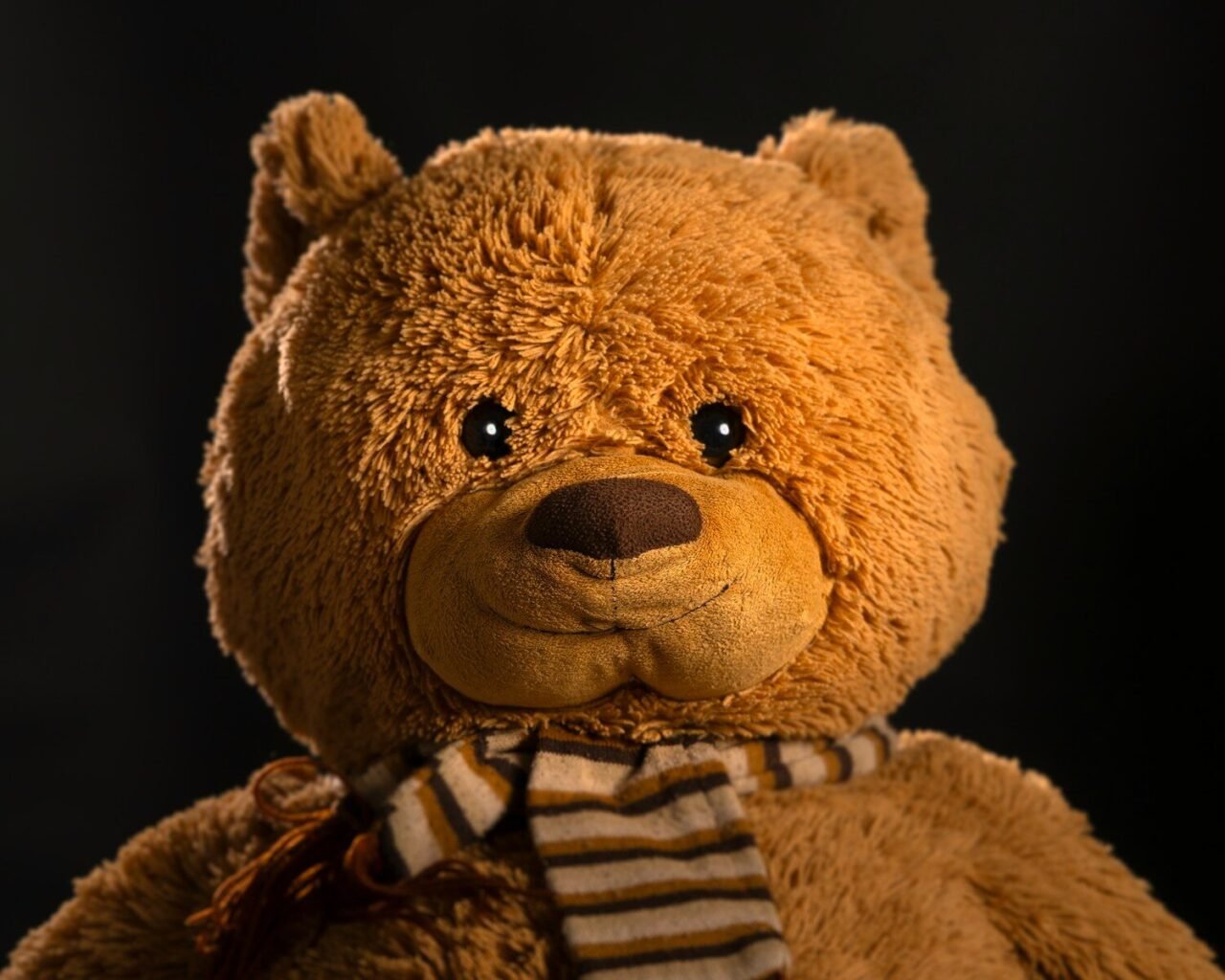 A brown teddy bear is posing for the camera.