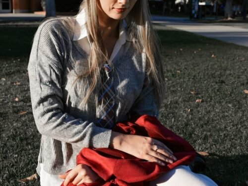 a woman sitting in the grass with her legs crossed