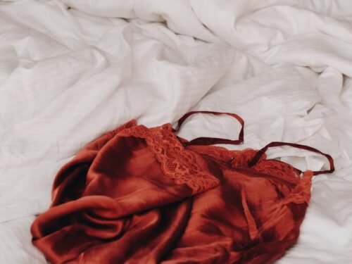 red lace brassiere on white textile