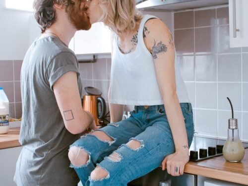 man and woman kissing inside kitchen