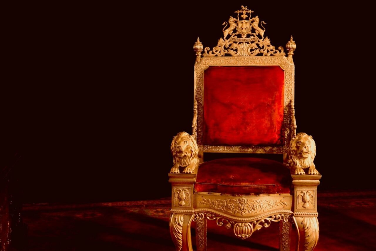 A gold and red chair sitting on top of a wooden floor