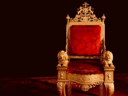 A gold and red chair sitting on top of a wooden floor