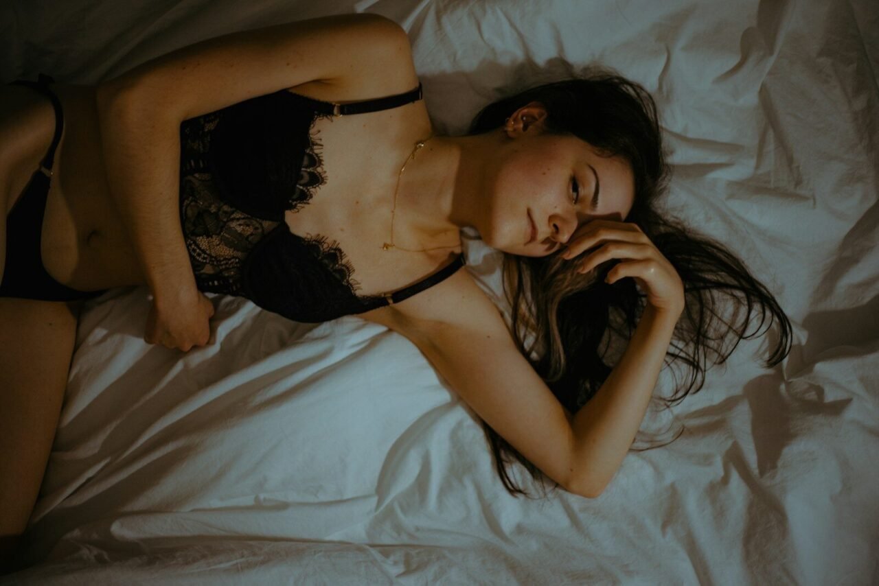 a woman laying on a bed wearing a black lingerie