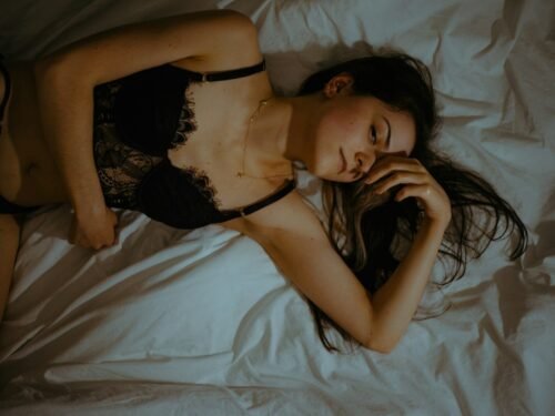 a woman laying on a bed wearing a black lingerie