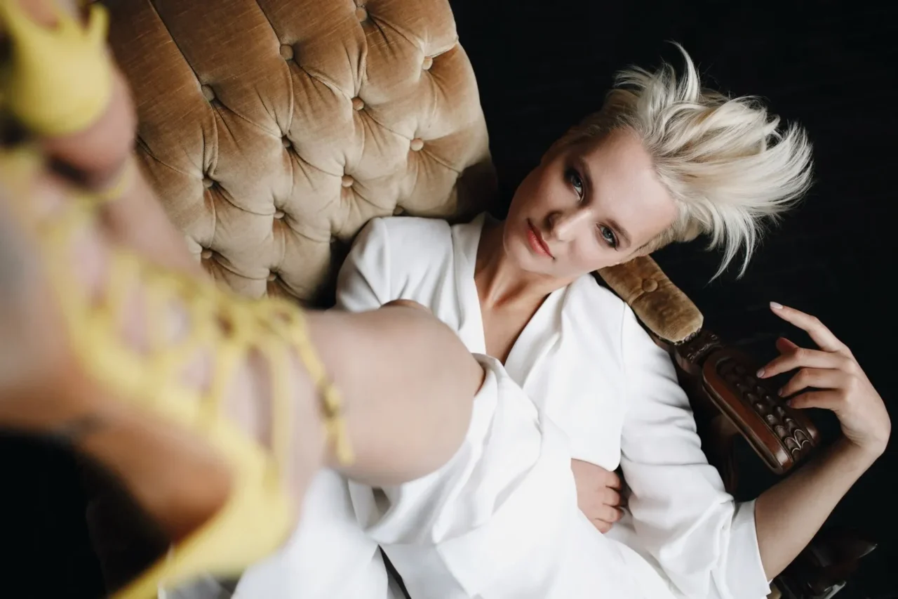 Gorgeous blonde fashion model white suit sits