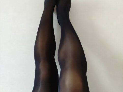 Legs in sheer black pantyhose on white background