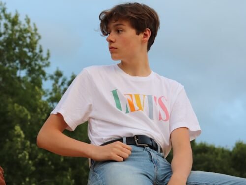 woman in white crew neck t-shirt and blue denim shorts sitting on brown wooden bench
