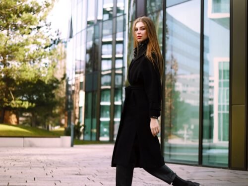 a woman in a black coat is walking down the street