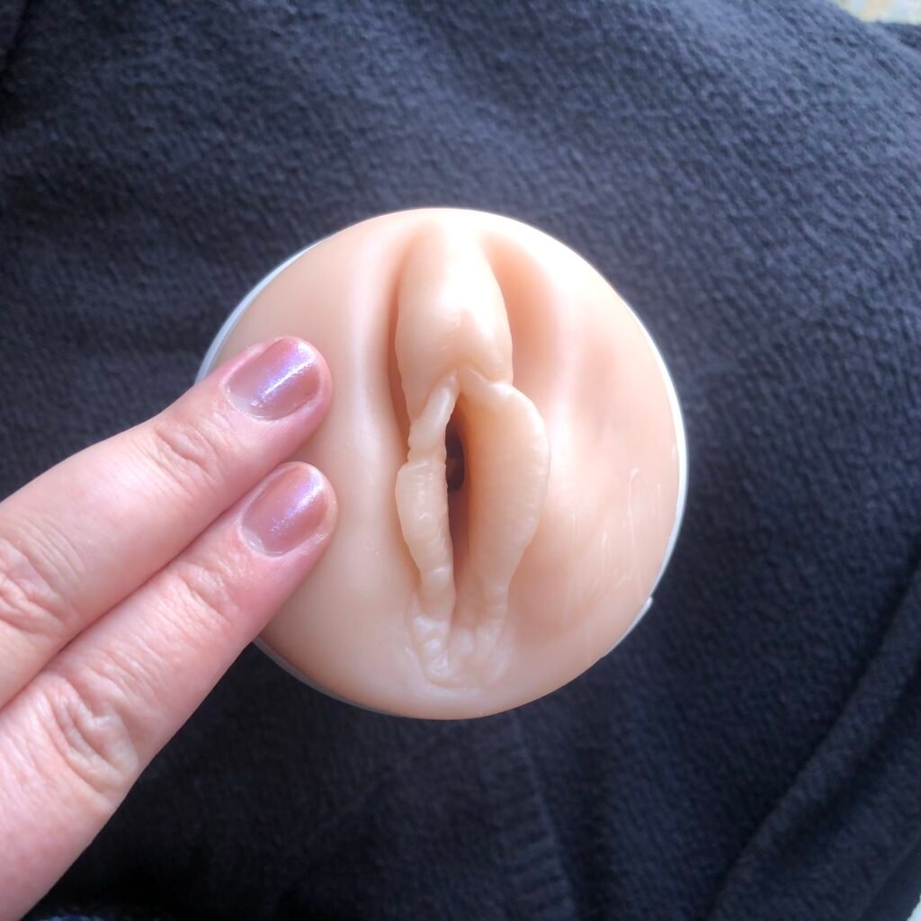 Two fingers circling the labia on a fleshlight