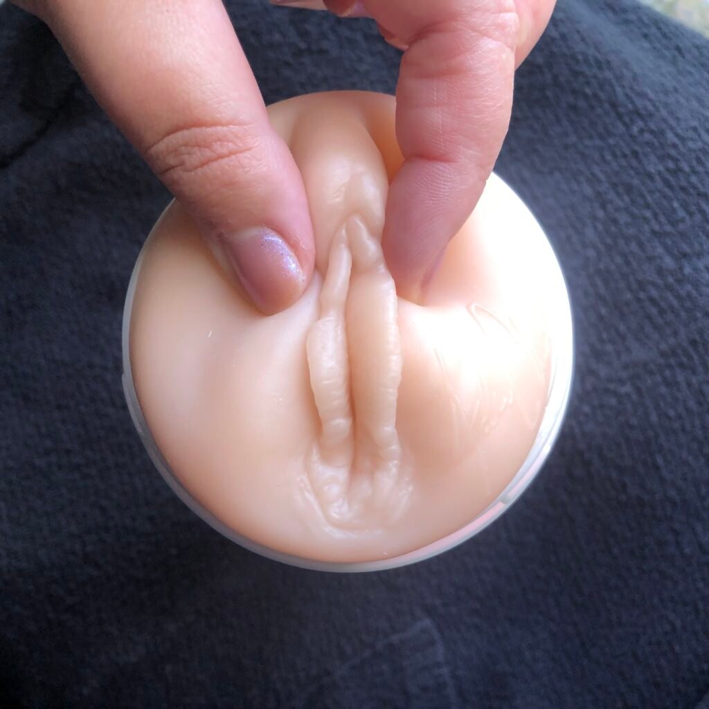 Two fingers pinching the labia on a fleshlight